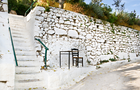 The entrance to a cafe with a huge white wall, table and chair, where anyone can read the menu and have some rest, Athens, Greece.の写真素材