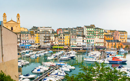 BASTIA, FRANCE - MAY 1, 2013: The small port with yachts, surrounded by the medieval houses, street cafes, tiny shops, with the St. Jean Baptiste church on the left, on May 1 in Bastia.のeditorial素材