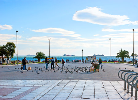 THESSALONIKI, GREECE - OCTOBER 17, 2013: People feed the doves on the Aristotle Square located next to the Nikis avenue (on the city's waterfront), on October 17 in Thessaloniki.のeditorial素材