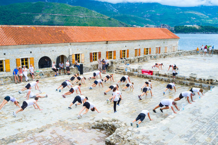 BUDVA, MONTENEGRO - JULY 12, 2014: The group of tourists get involved in fitness in the old Venetian citadel, enjoying the view on the foggy mountains and sea, on July 12 in Budva.のeditorial素材