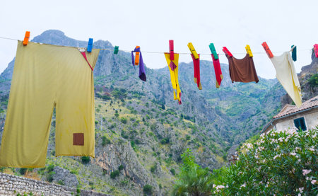The shorts and socks are drying on big colorful wooden pins on one of the central squares of the Stari Grad, Kotor, Montenegro.のeditorial素材
