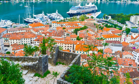 KOTOR, MONTENEGRO - JULY 15, 2014: The ruins of the old Venetian fortress with red tile roofs and cruise liner in harbour, on July 15 in Kotor.のeditorial素材