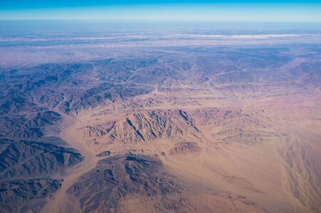 The yellow plain surrounded by the black rocks in Egyptian Sahara.の写真素材