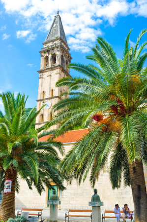 PERAST, MONTENEGRO - JULY 13, 2014: The St Nicholas Church located on main town square, surrounded by palms with the cozy benches, on July 13 in Perast.のeditorial素材