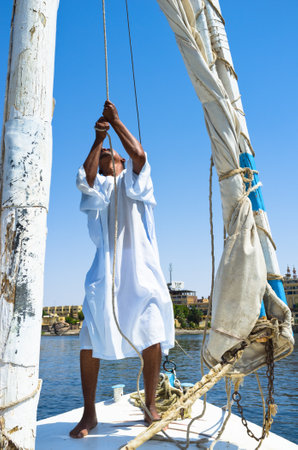 The boatman sets the sail on the traditional Egyptian boat, named felucca, Aswan, Egypt.のeditorial素材