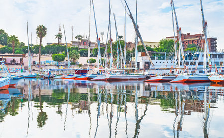 LUXOR, EGYPT - OCTOBER 8, 2014: The green embankment and colorful feluccas reflects in the clear and calm waters of the Nile river, on October 8 in Luxor.のeditorial素材