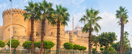 The lush palms hide the medieval Saladin Citadel, located on the hill and surrounded by the huge ramparts, Cairo, Egypt.のeditorial素材