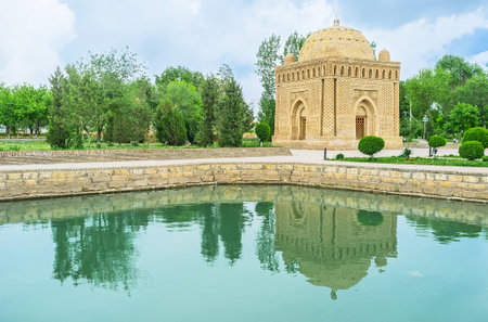 The Samanid mausoleum reflects in the tiny pond, located in recreation park, Bukhara, Uzbekistan.のeditorial素材