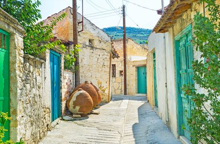 The narrow street with the small stone houses, colorful wooden doors and old amphoras, Omodos, Cyprus.の写真素材