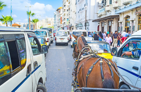 ALEXANDRIA, EGYPT - OCTOBER 11, 2014: The traffic jam at the city promenade with numerous taxi buses and horse carriages, on October 11 in Alexandria.のeditorial素材