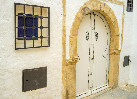 The old stone door frame and wooden door in traditional arabic form, Hammamet, Tunisia.の写真素材