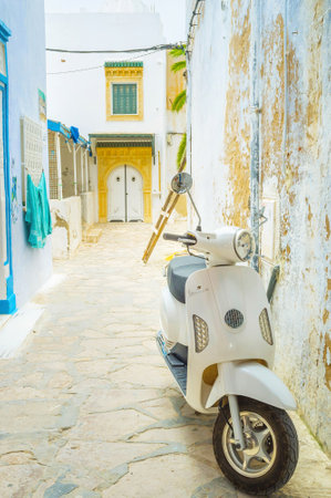 HAMMAMET, TUNISIA - SEPTEMBER 6, 2015: Scooter is the comfortable and maneuver transport in the narrow streets of Medina, on September 6 in Hammamet.のeditorial素材