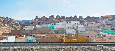 The old taxi next to the railroad with the colorful village houses on the background, Aswan suburb, Egypt.の写真素材