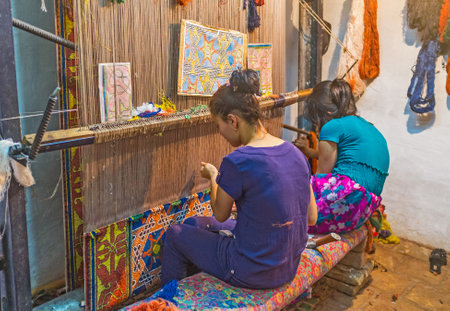 KHIVA, UZBEKISTAN - MAY 3, 2015: Two young girl make the traditional Uzbek woven-rug in the workshop, on May 3 in Khiva.のeditorial素材