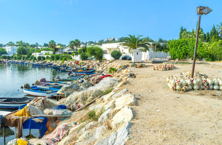 CARTHAGE, TUNISIA - SEPTEMBER 2, 2015: The ancient Punic port nowadays became the village fishing harbor with many colorful boats and clay pots for octopus on the bank, on September 2 in Carthage.のeditorial素材