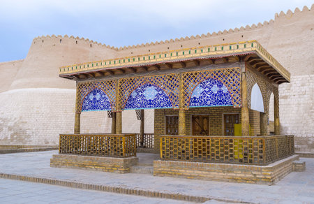 The tiny shop decorated with traditional Uzbek pattern with the medieval fortress wall on the background, Khiva.のeditorial素材