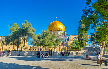 JERUSALEM, ISRAEL - FEBRUARY 16, 2016: The elderly Palestinian muslims spend their time and read Quran in the shade of trees next to Al-Aqsa Mosque and the Dome of the Rock, on February 16 in Jerusalem.のeditorial素材