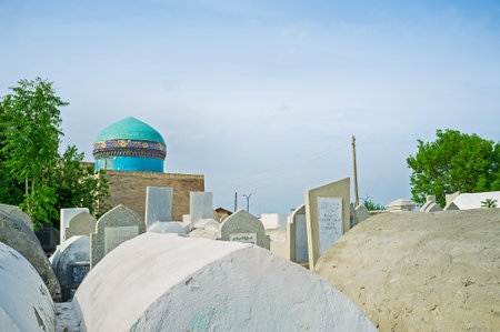 KOKAND, UZBEKISTAN - MAY 6, 2015: The old cemetery with the blue dome of Madari Khan Mausoleum on the background, on May 6 in Kokand.のeditorial素材