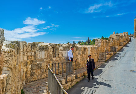 JERUSALEM, ISRAEL - FEBRUARY 18, 2016: The old Hasid walk along the descent on Batei Mahase street with the view on the medieval city ramparts, on February 18 in Jerusalem.のeditorial素材