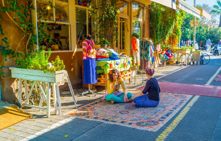 TEL AVIV, ISRAEL - FEBRUARY 25, 2016: The sellers from the clothes workshop sit cross-legged on the rug in market street of old Jaffa, on February 25 in  Tel Aviv.のeditorial素材