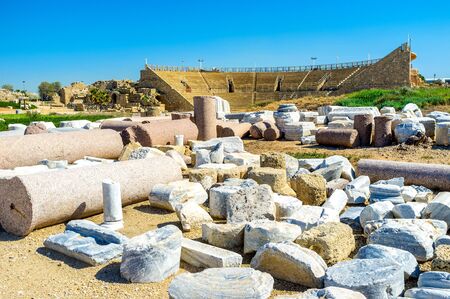 The preserved and restored part of the ancient Colosseum, surrounded by the artifacts and ruined buildings, Caesarea, Israel.の写真素材