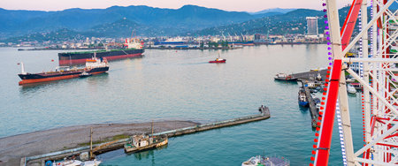 The ferris wheel is the best viewpoint, overlooking the distant mountains, cargo port and ships, clear waters, reflecting the sunset sky, Batumi, Georgia.のeditorial素材