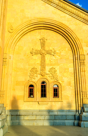 The carved arch, cross and floral ornaments on the stone wall of Sameba Cathedral in Tbilisi,...