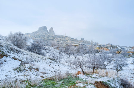 The snowy valley and the Uchisar historic village, topped with the natural rock citadel, the notable landmark of Cappadocia, Turkey.のeditorial素材