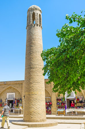 SHAKHRISABZ, UZBEKISTAN - MAY 2, 2015: The minaret of the Kok Gumbaz (Blue Dome) Mosque with the tourist stalls on the background, on May 2 in Shakhrisabz.のeditorial素材