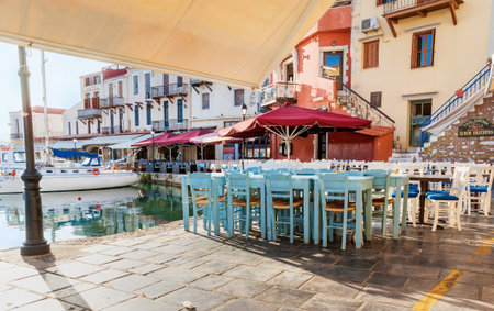 RETHYMNO, GREECE - OCTOBER 16, 2013: The wooden chairs and tables of the outdoor cafes and taverns in the old harbor, on October 16 in Rethymno.のeditorial素材
