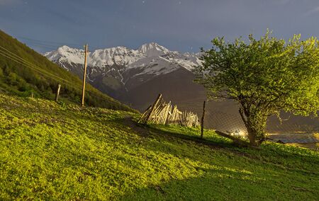 The night view of the meadow on the mountain slope and snowy mountain range on background, Mestia,...