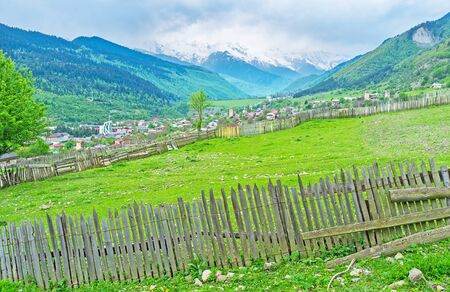 The green pasture separated with old wooden fence, Mestia, Upper Svaneti, Georgia.
