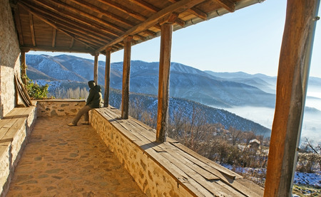 The old stone terrace with the wooden pillars overlooks the misty mountains around Kastoria, Greece.の写真素材