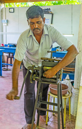 MEETIYAGODA, SRI LANKA - DECEMBER 5, 2016: The silversmith makes the silver wire, using the hand jewelry rolling mill, on December 5 in Meetiyagoda.のeditorial素材