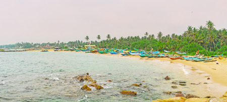 Panorama of the sand beach, occupied with the colorful wooden fishing boats, Hikkaduwa, Sri Lanka.の写真素材