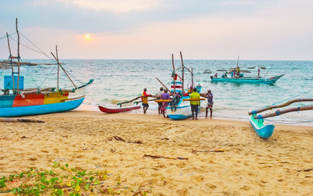 HIKKADUWA, SRI LANKA - DECEMBER 5, 2016: The last boats back from the evening fishing and fishermen steer them on the sand, on December 5 in Hikkaduwa.のeditorial素材