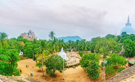 Panorama of Mihintale Temple - the Ambasthala Dagoba, surrounded by ancient vatadage pillars, located on the plain among the palms, the Aradhana Gala Rock and giant Maha Stupa are on its sides, Sri Lanka.のeditorial素材
