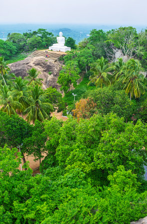 The Buddha Statue on the rocky hill among the gardens of Mihintale Temple, Sri Lanka.のeditorial素材