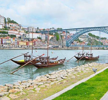 Traditional Rabelo boats laden with port wine barrels with the old Porto and Luis I Bridge on the background, Portugal.の写真素材