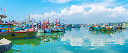 MIRISSA, SRI LANKA - DECEMBER 3, 2016: The colorful fishing trawlers and old motor boats reflect in bright blue waters of the fisheries harbor, on December 3 in Mirissa.のeditorial素材
