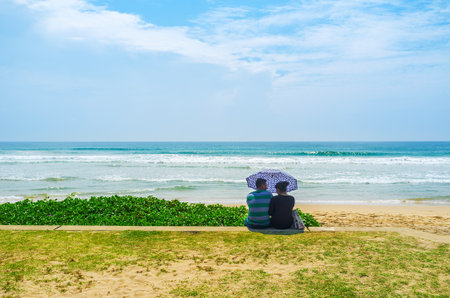 MATARA, SRI LANKA - DECEMBER 3, 2016: Happy young couple spends the time at the Beach Road under umbrella, on December 3 in Matara.のeditorial素材