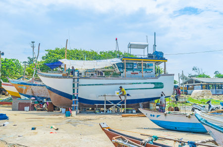 MIRISSA, SRI LANKA - DECEMBER 3, 2016: The fishermen repair and paint their trawler at the shore of the large fisheries harbor, on December 3 in Mirissa.のeditorial素材