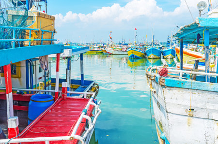 The view on fisheries harbor through the space between two colorful trawlers, Mirissa, Sri Lanka.のeditorial素材