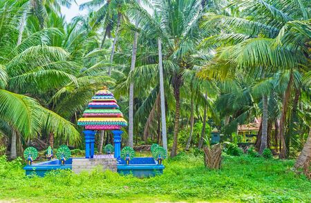 The colorful fountain with peacocks (the vehicle of God Murugan) in lush garden, located next to the Murugan Temple, Chilaw, Sri Lanka.の写真素材