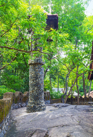 The old belfry of Padeniya Buddhist Temple is hidden among the trees on the top of sacred rock, Padeniya, Sri Lanka.の写真素材