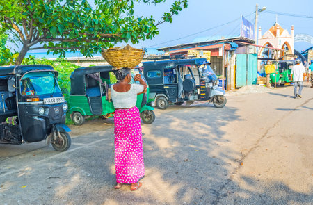 NEGOMBO, SRI LANKA - NOVEMBER 25, 2016: The elderly woman goes to the Main Fish Market along the tuk...