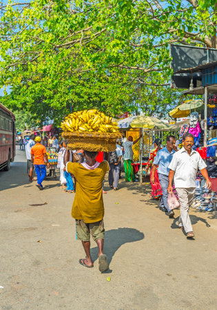 COLOMBO, SRI LANKA - DECEMBER 6, 2016: The porter at Pettah Market carries the basket with bananas...