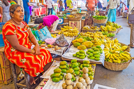 COLOMBO, SRI LANKA - DECEMBER 6, 2016: The fruit seller at Fose Market in Pettah, repeats the prices of bananas, papayas and wooden apple fruits to attract the clients, on December 6 in Colombo.のeditorial素材