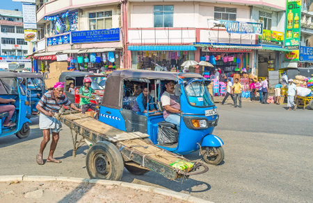 COLOMBO, SRI LANKA - DECEMBER 6, 2016: The senior porter moves along the car road at the busy Gas Works Junction, surrounded by markets of Pettah, on December 6 in Colombo.のeditorial素材