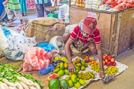 COLOMBO, SRI LANKA - DECEMBER 6, 2016: The aged seller arranges the small heaps of fruits on the floor in Fose Market in Pettah, on December 6 in Colombo.のeditorial素材